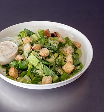 Caesar salad with croutons and a side of dressing