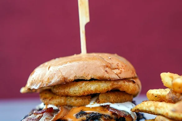 Smash burger with bacon and an onion ring, with fries