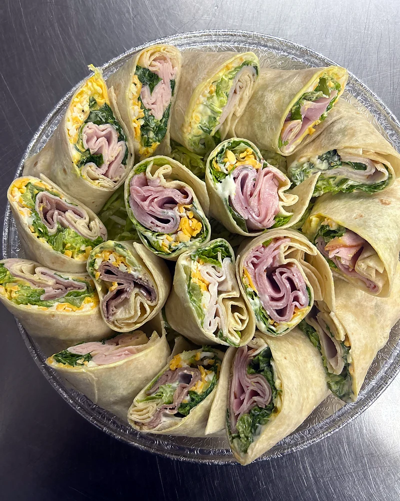 Platter of sliced turkey, ham and veggie wraps