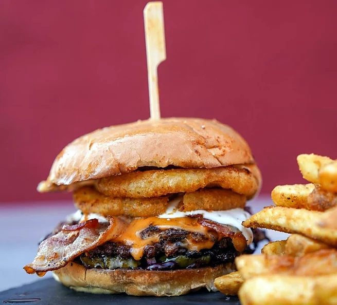 Smash burger with bacon and an onion ring, with fries