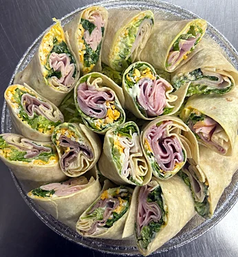 Platter of sliced turkey, ham and veggie wraps