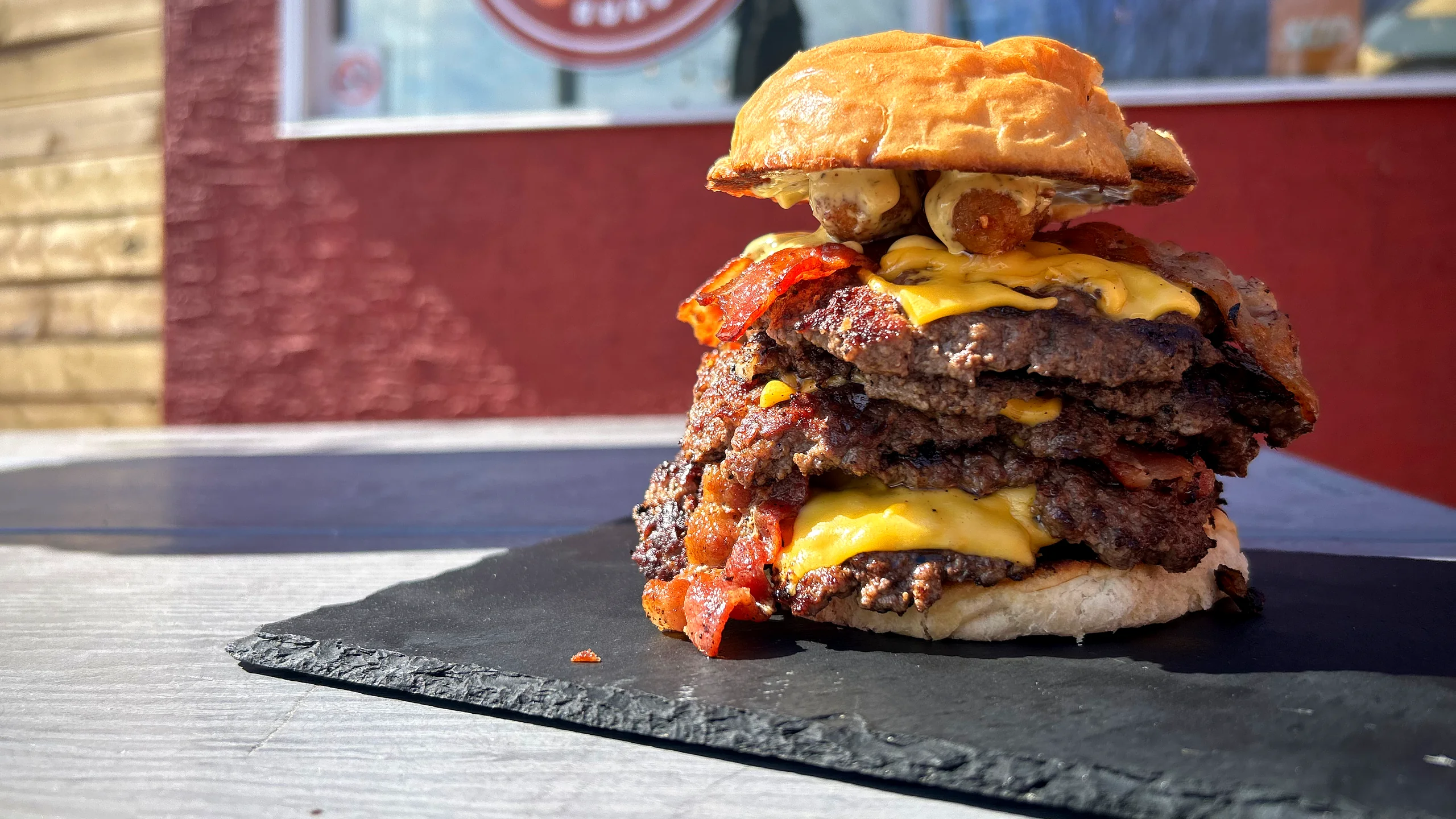 Triple smash burger with bacon and melted cheese on a slate board at Woodbine Burgers