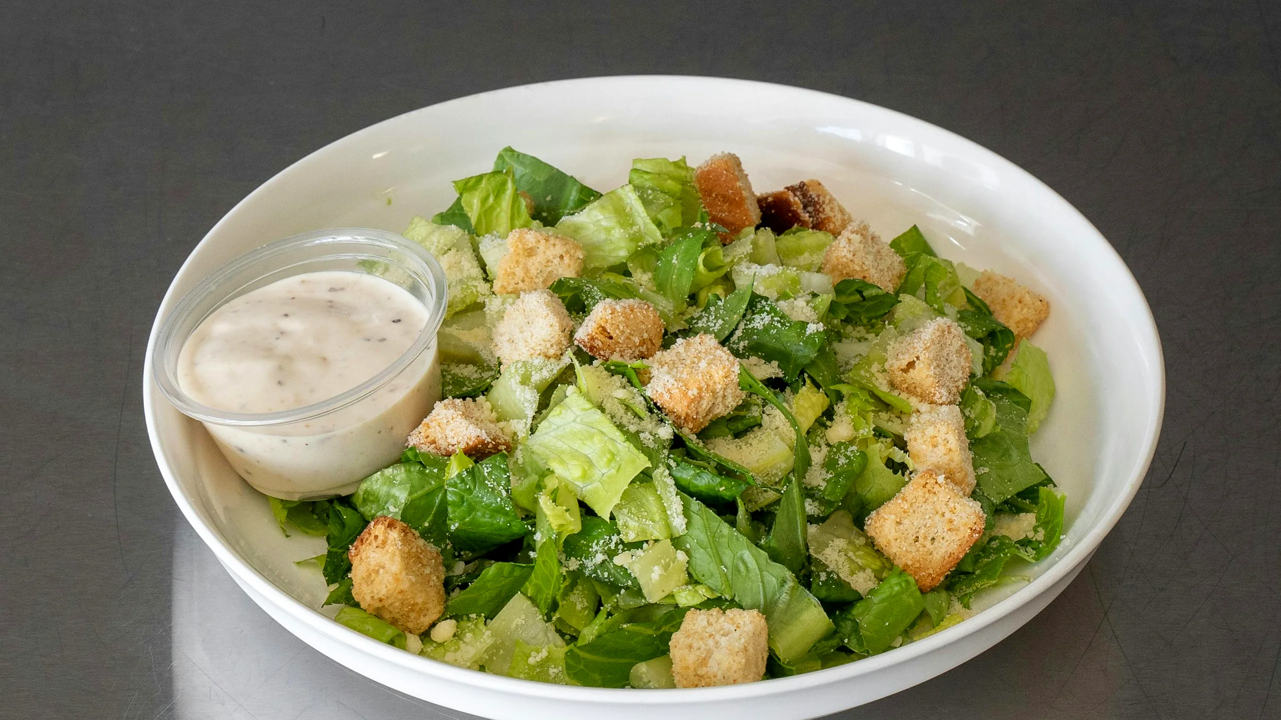 Caesar salad with croutons and a side of dressing