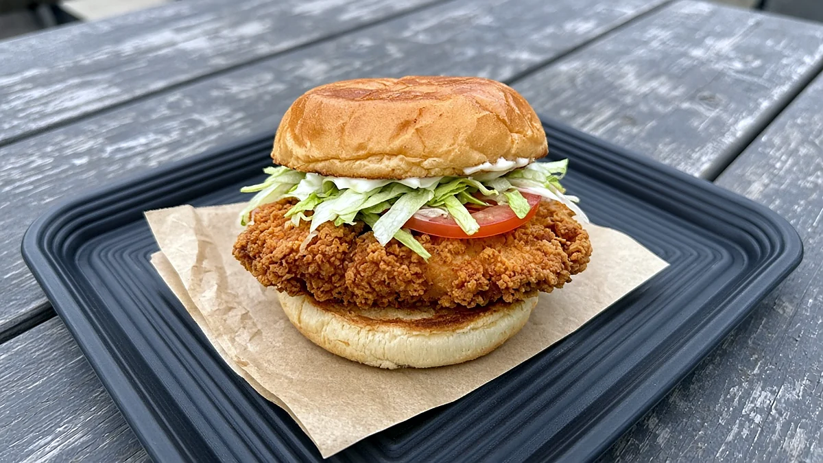 Crispy breaded chicken burger with lettuce and tomato on a tray