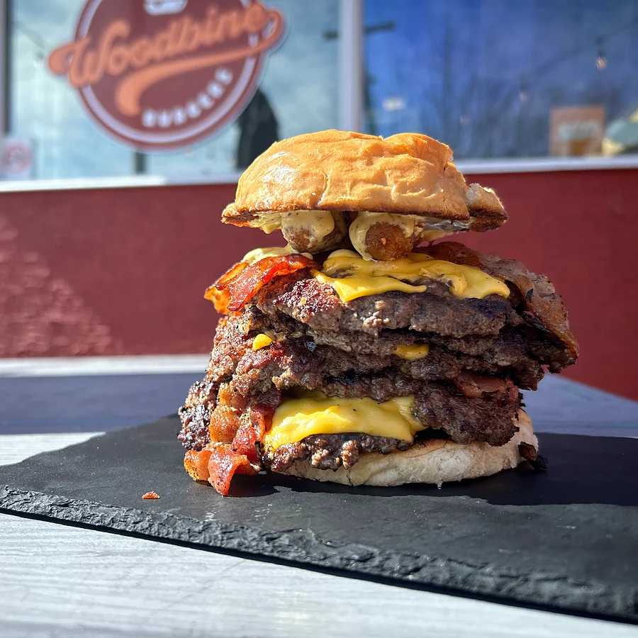 Triple smash burger with bacon and melted cheese on a slate board